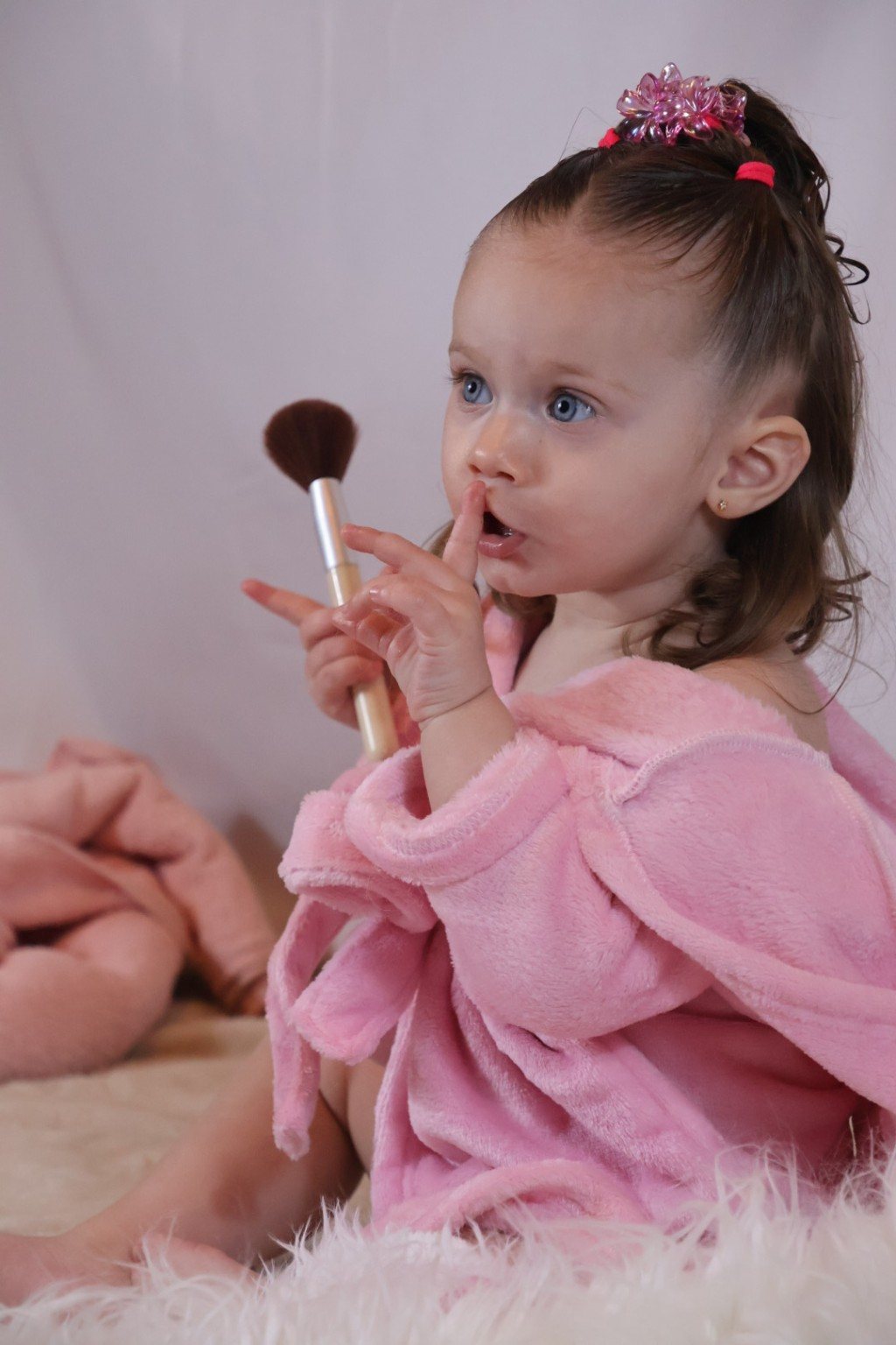 Petite fille découvrant un pinceau de maquillage