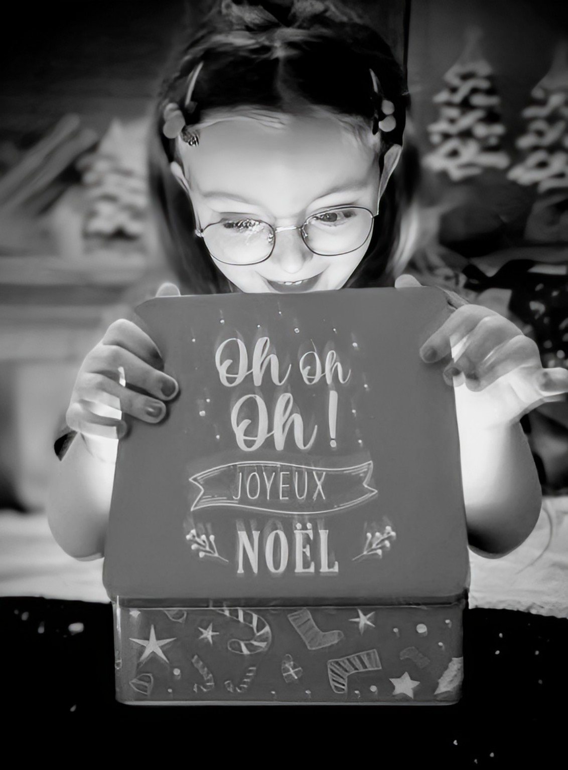 Enfant découvrant une boîte de Noël lumineuse